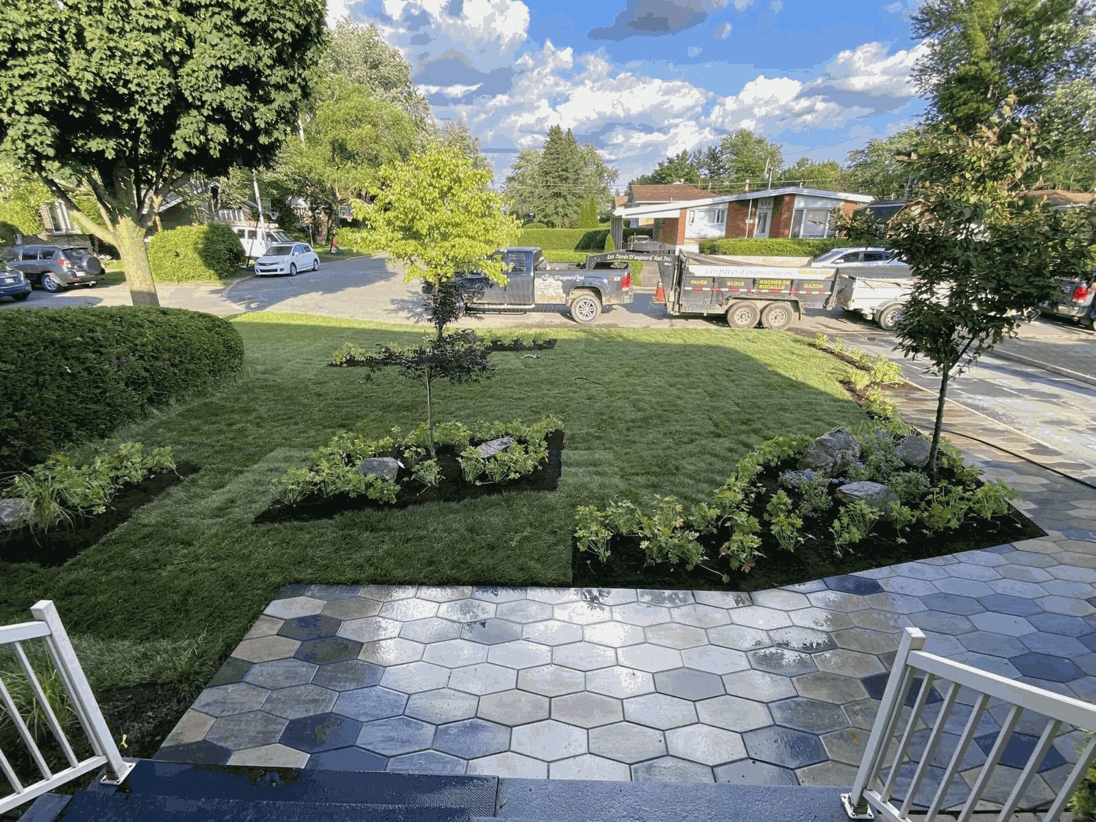 Hexagonal paver walkway and new landscaping, with the company truck and trailer parked out front