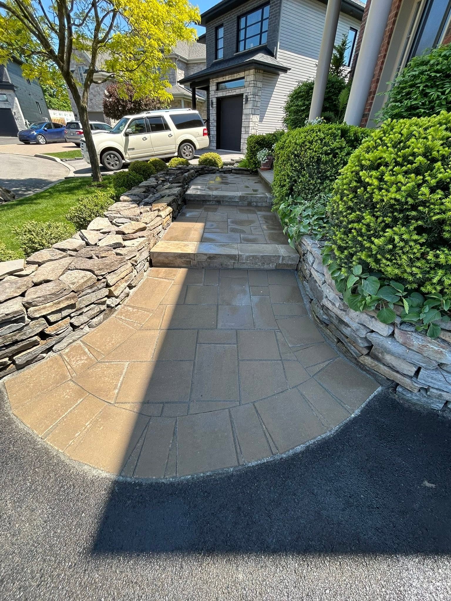 Fan-laid paver driveway with a natural stone wall