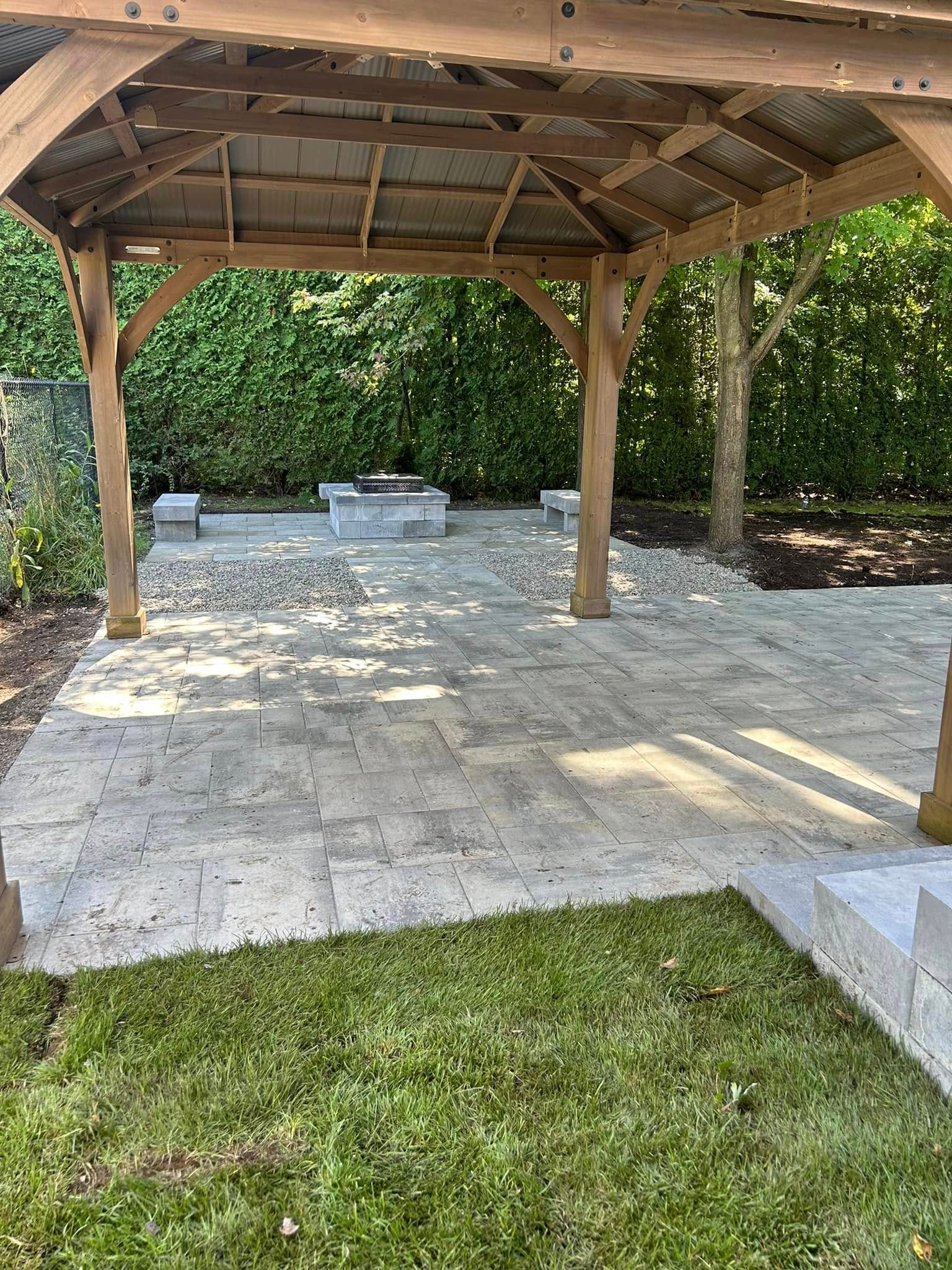 Paver patio under a pergola with a fire pit corner